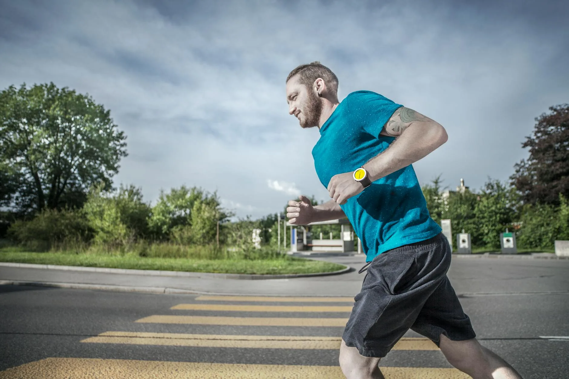 Runner checking budget GPS watch on wrist mid-run on sunny trail path