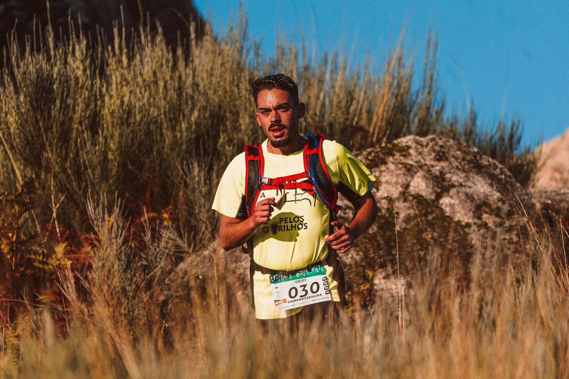 Runner wearing a loaded trail backpack during an ultramarathon on a mountain path