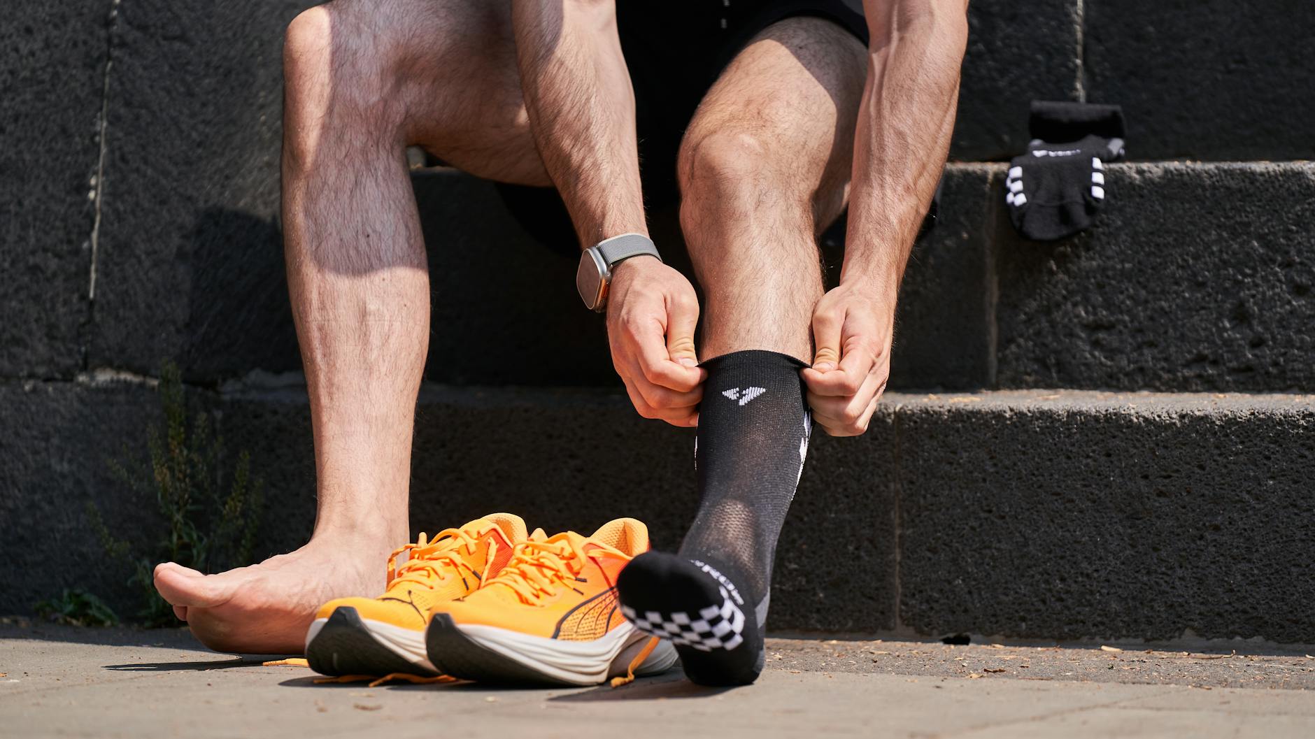 Runner wearing bright compression socks mid-stride on a sunny road