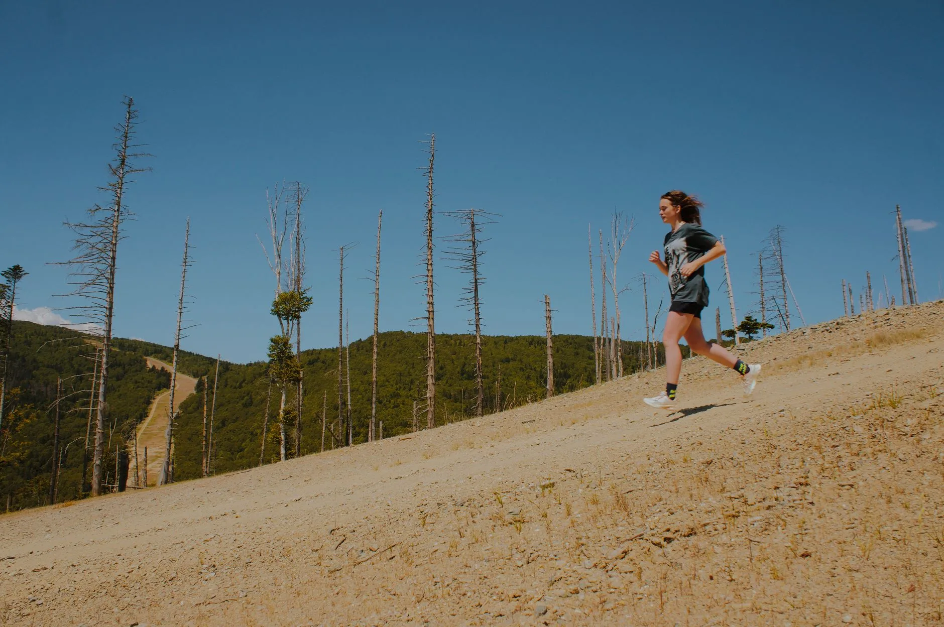 Runner sprinting uphill on a steep trail during an outdoor hill training session