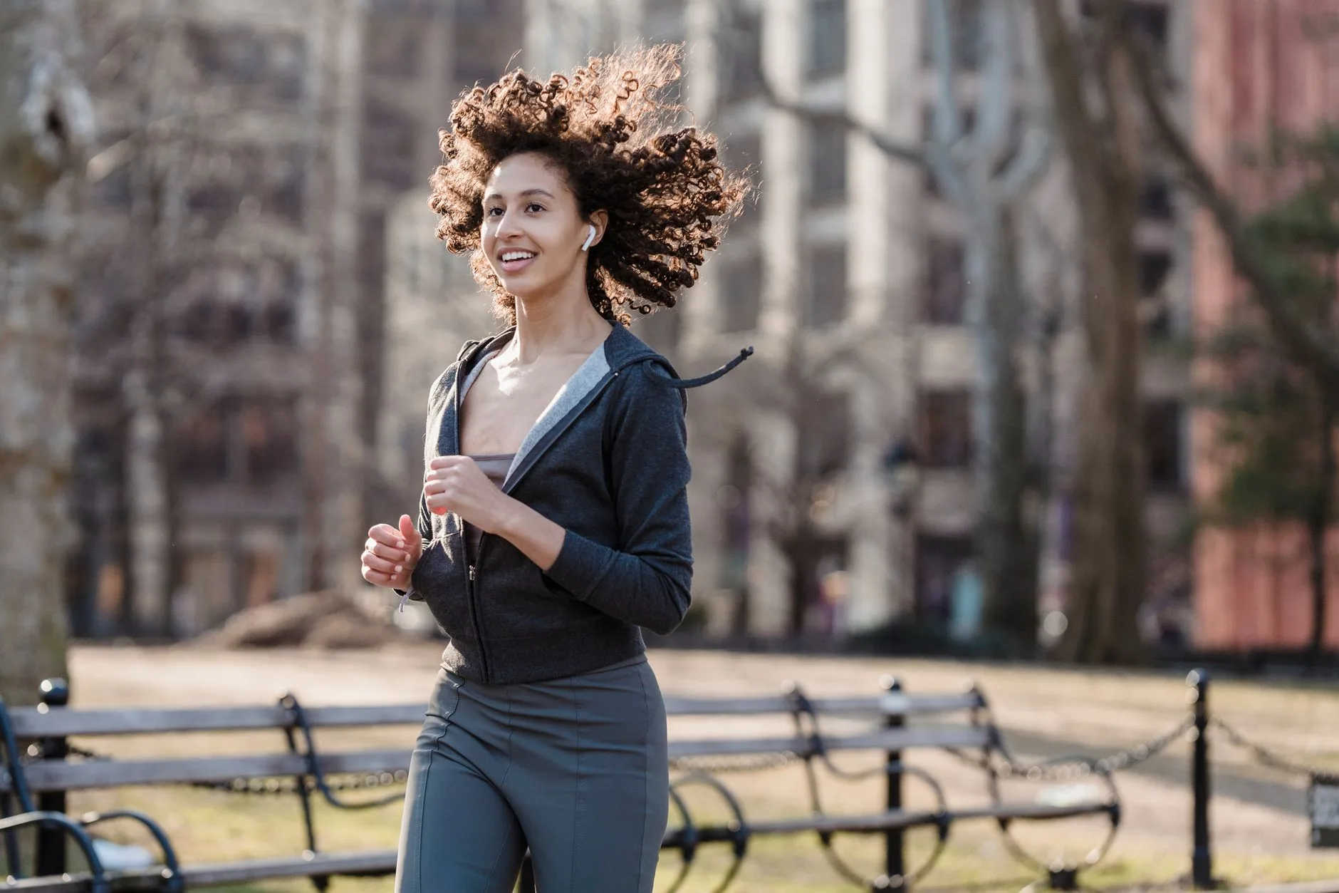 Runner smiling while listening to music on a sunny outdoor trail