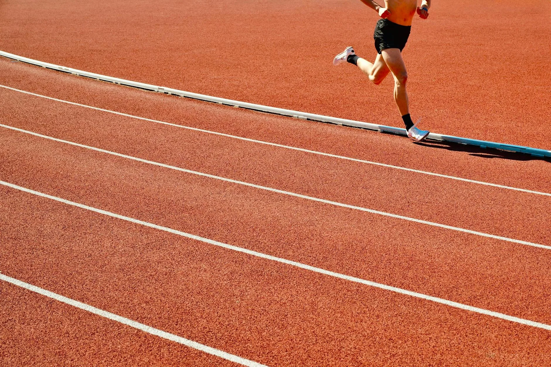 Runner sprinting on track, focused form, demonstrating speed work technique