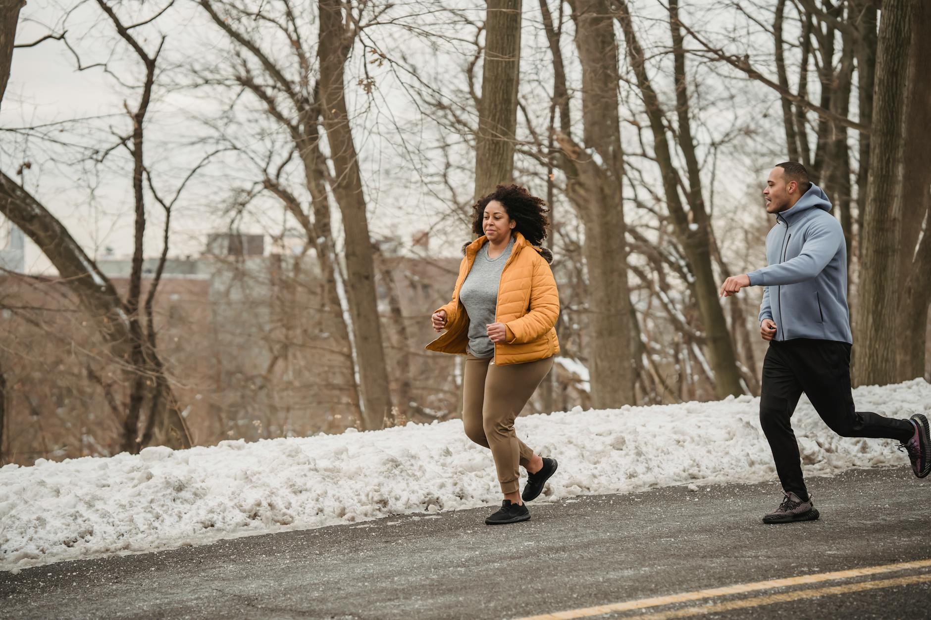 Runner in bright winter gear jogging through snowy path, breath visible in cold air