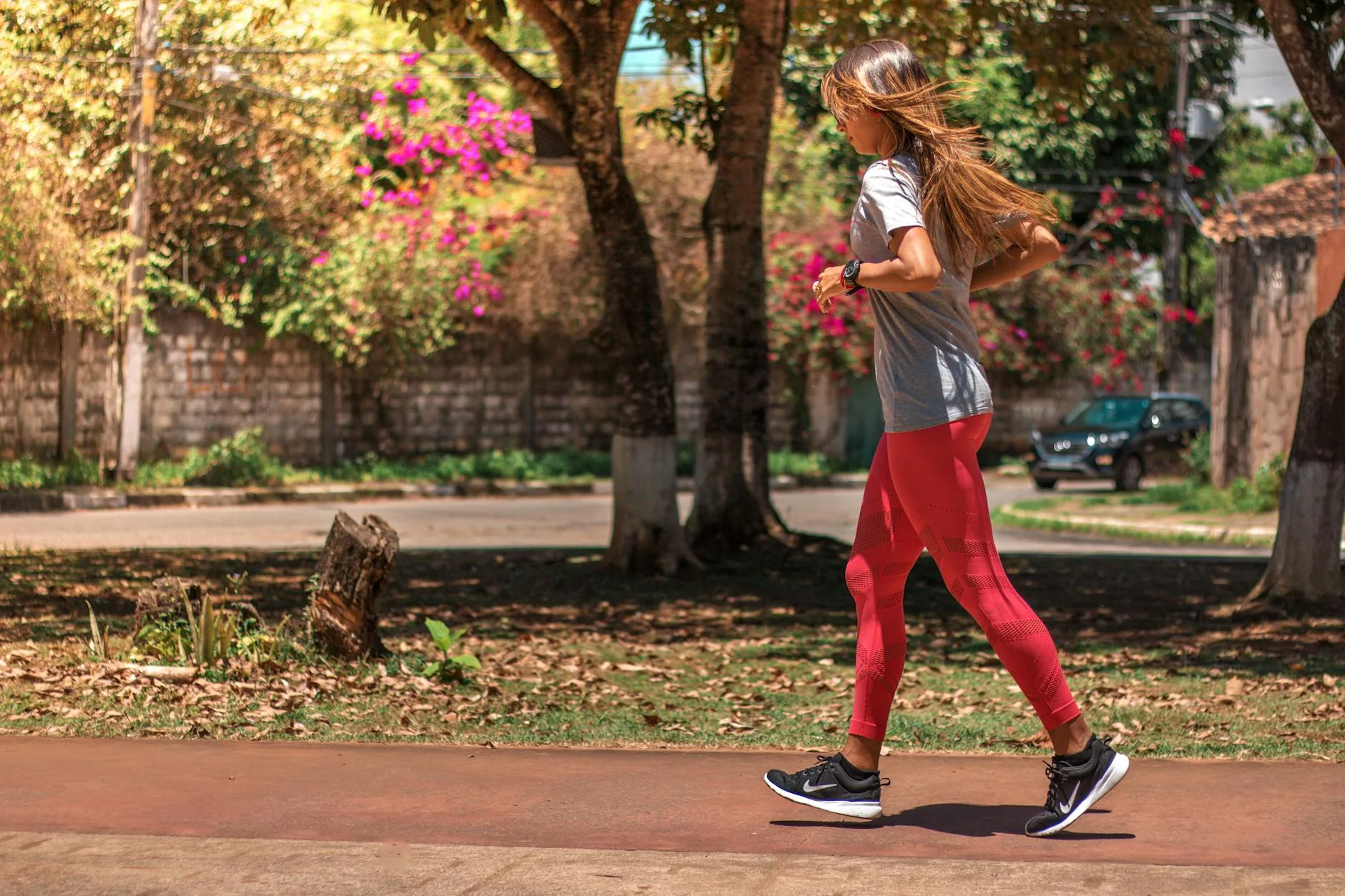 Runner checking watch while jogging through a busy city street at dawn