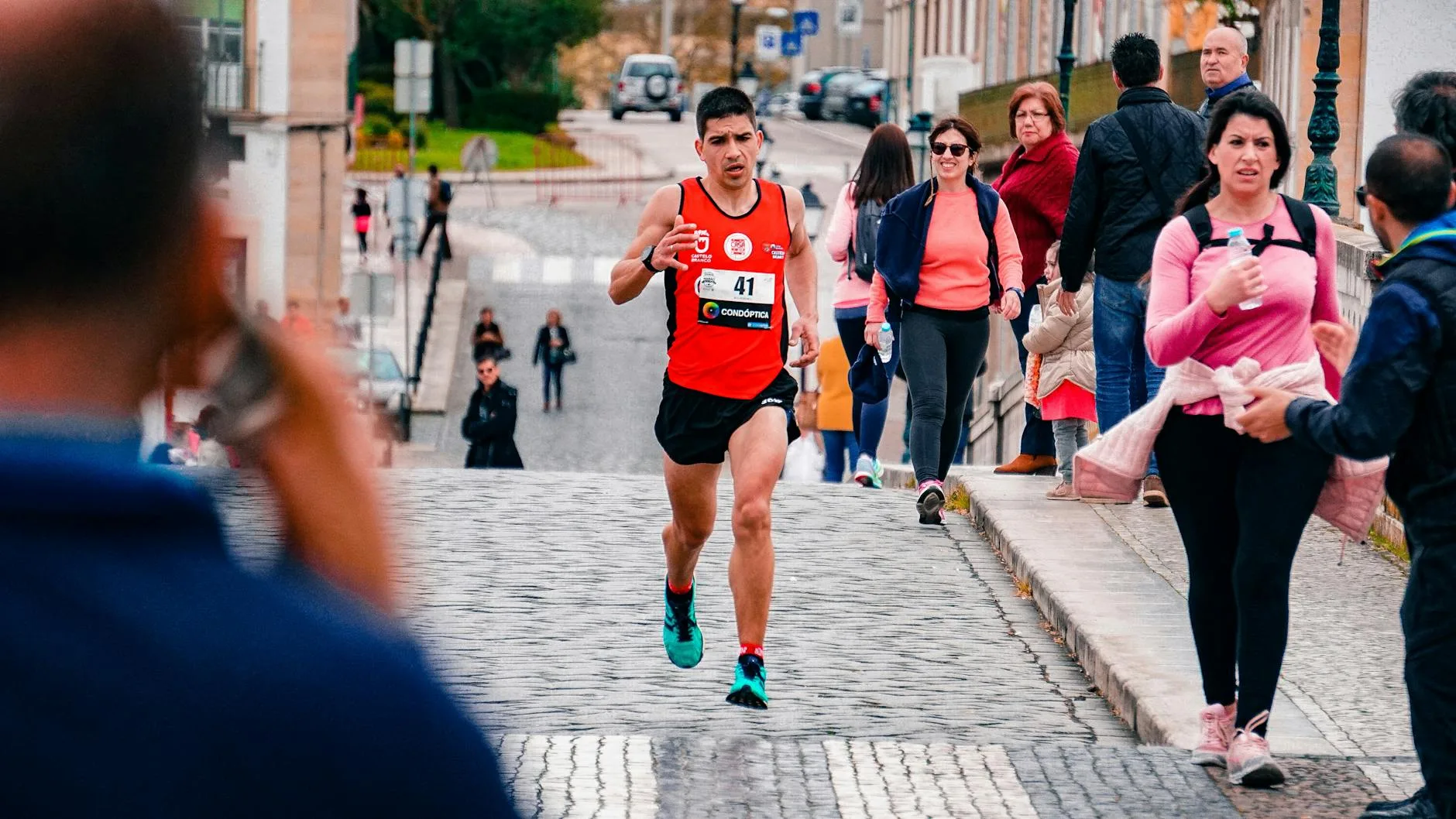 Runner clutching stomach in pain during a race, grimacing mid-stride on track