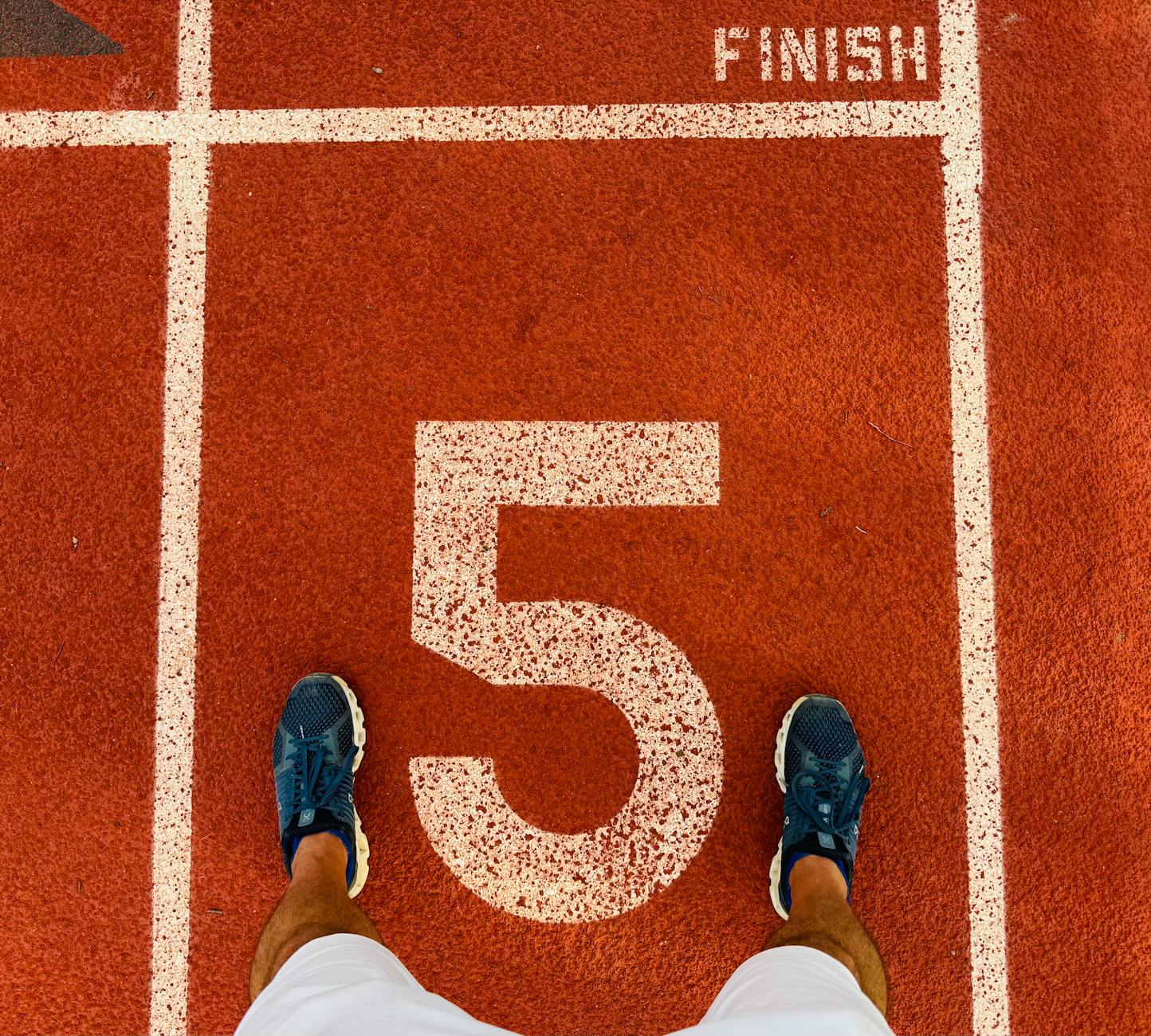 Average runner setting goals on a track, determined expression, stopwatch in hand
