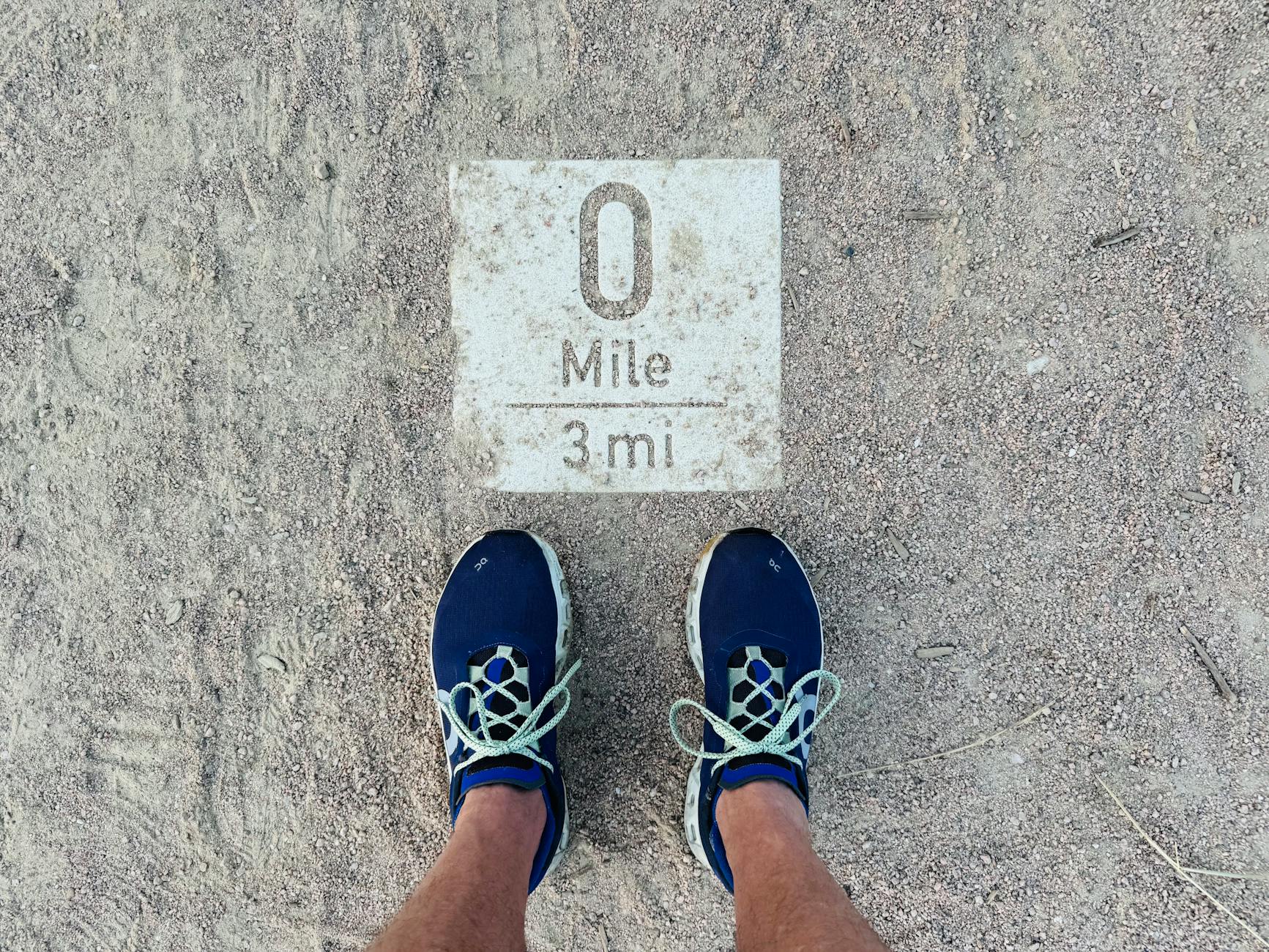 Runner comparing trail and road running shoes on dirt path outdoors