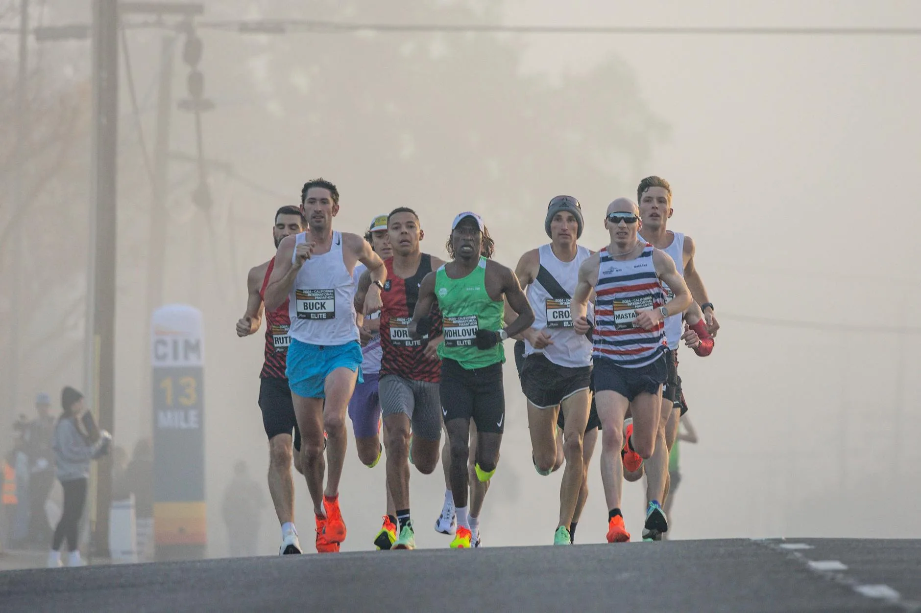 Beginner runner crossing half marathon finish line with arms raised in triumph