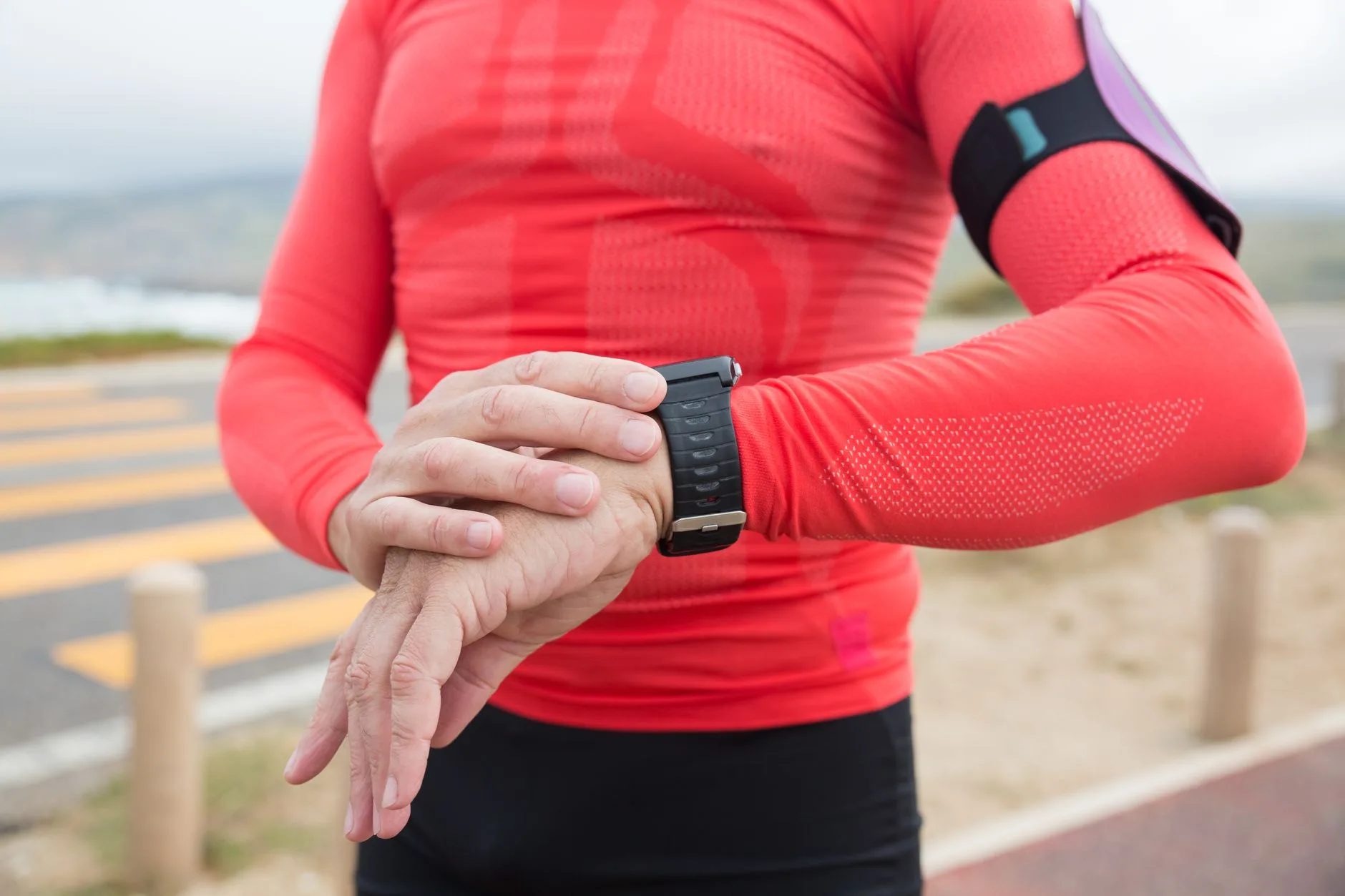 Beginner runner checking a GPS running watch on their wrist during an outdoor jog in the UK