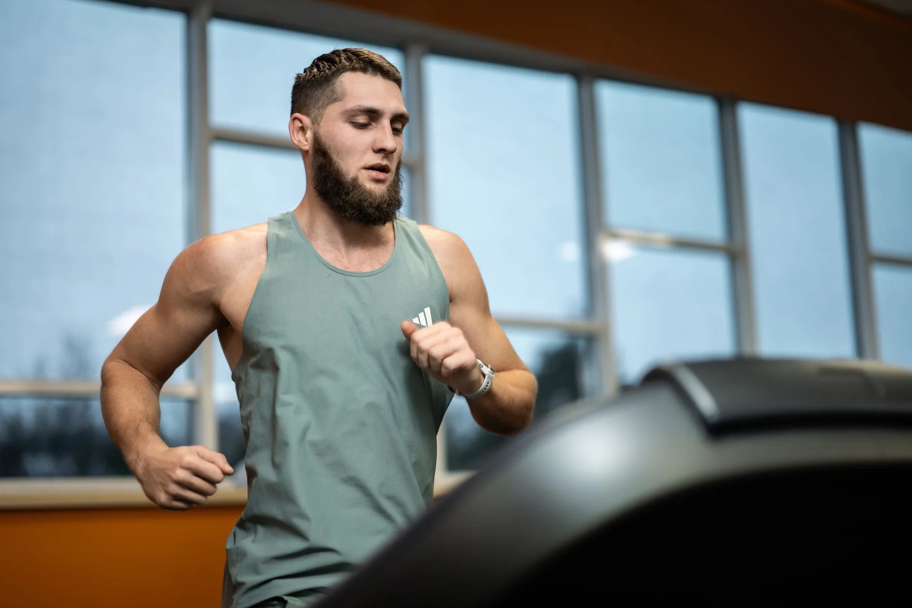 Runner sprinting on track, lean muscles visible, showcasing strength built through running