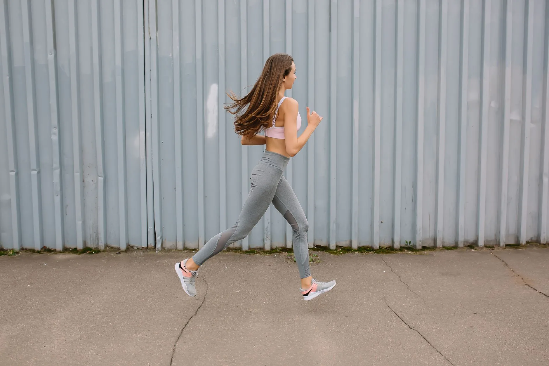 Runner clutching their side in pain during an outdoor run on a sunny trail.