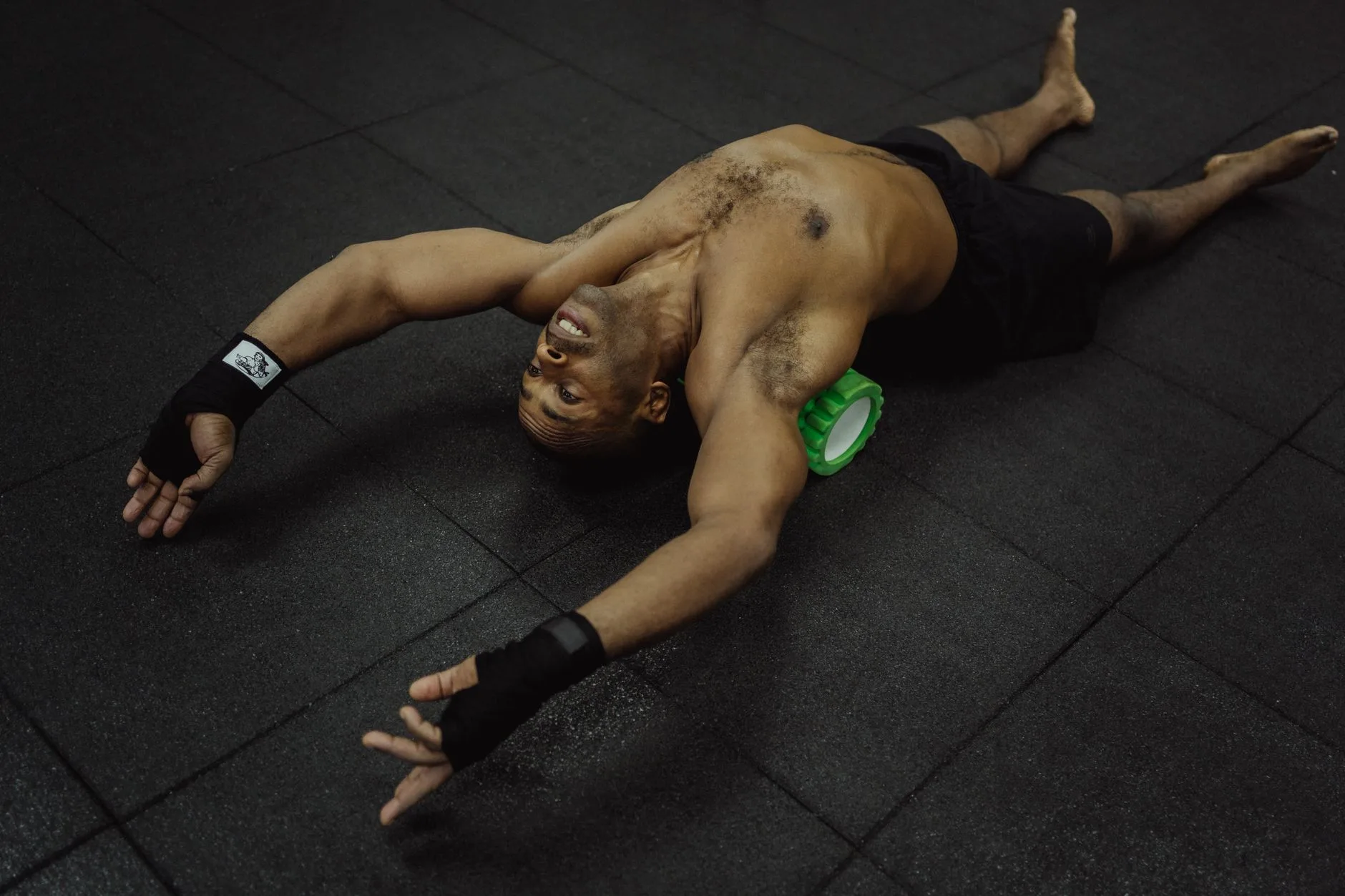 Runner stretching and resting with water bottle after crossing finish line