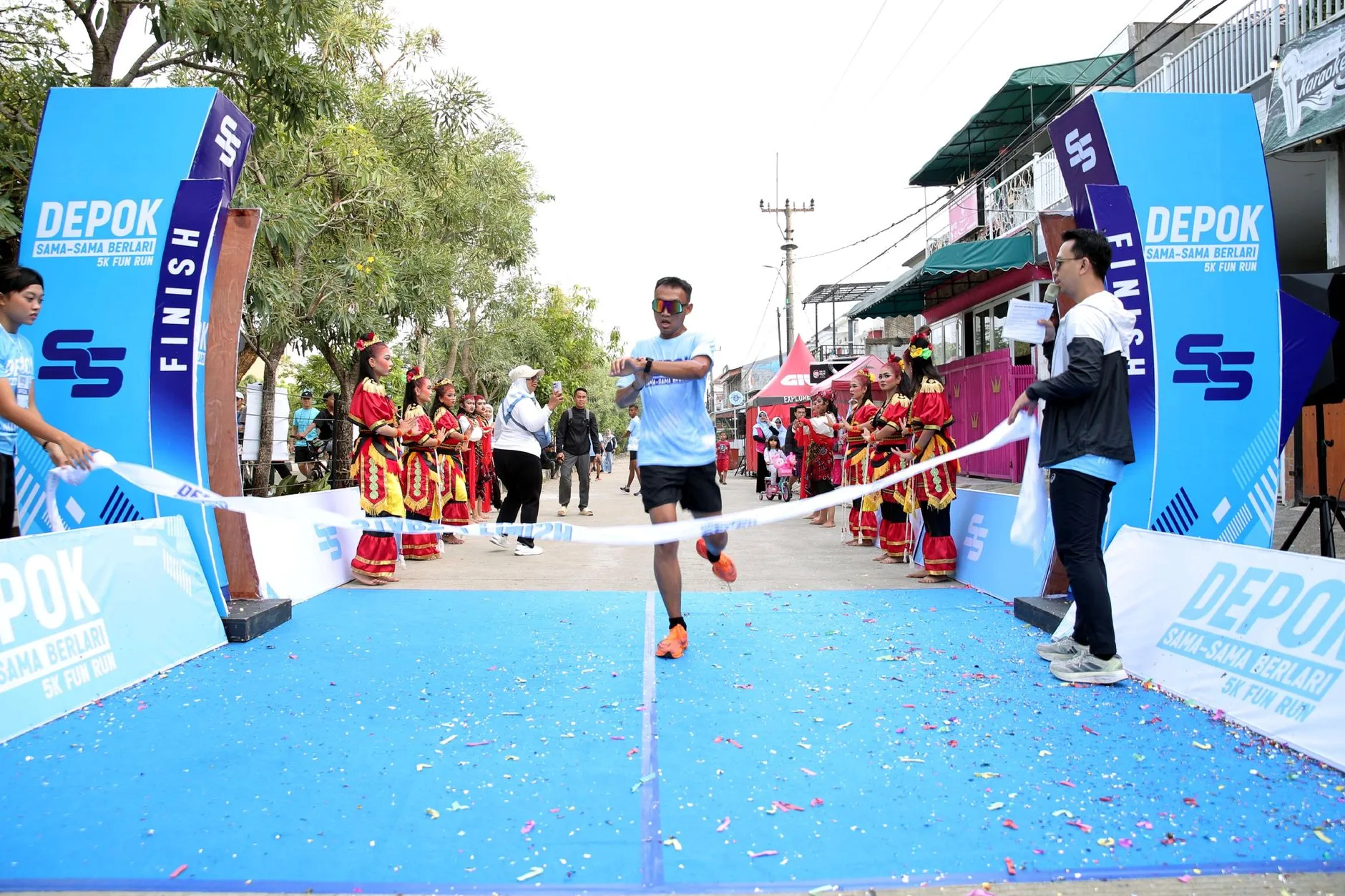 Beginner runner crossing a 5K finish line with arms raised in triumph
