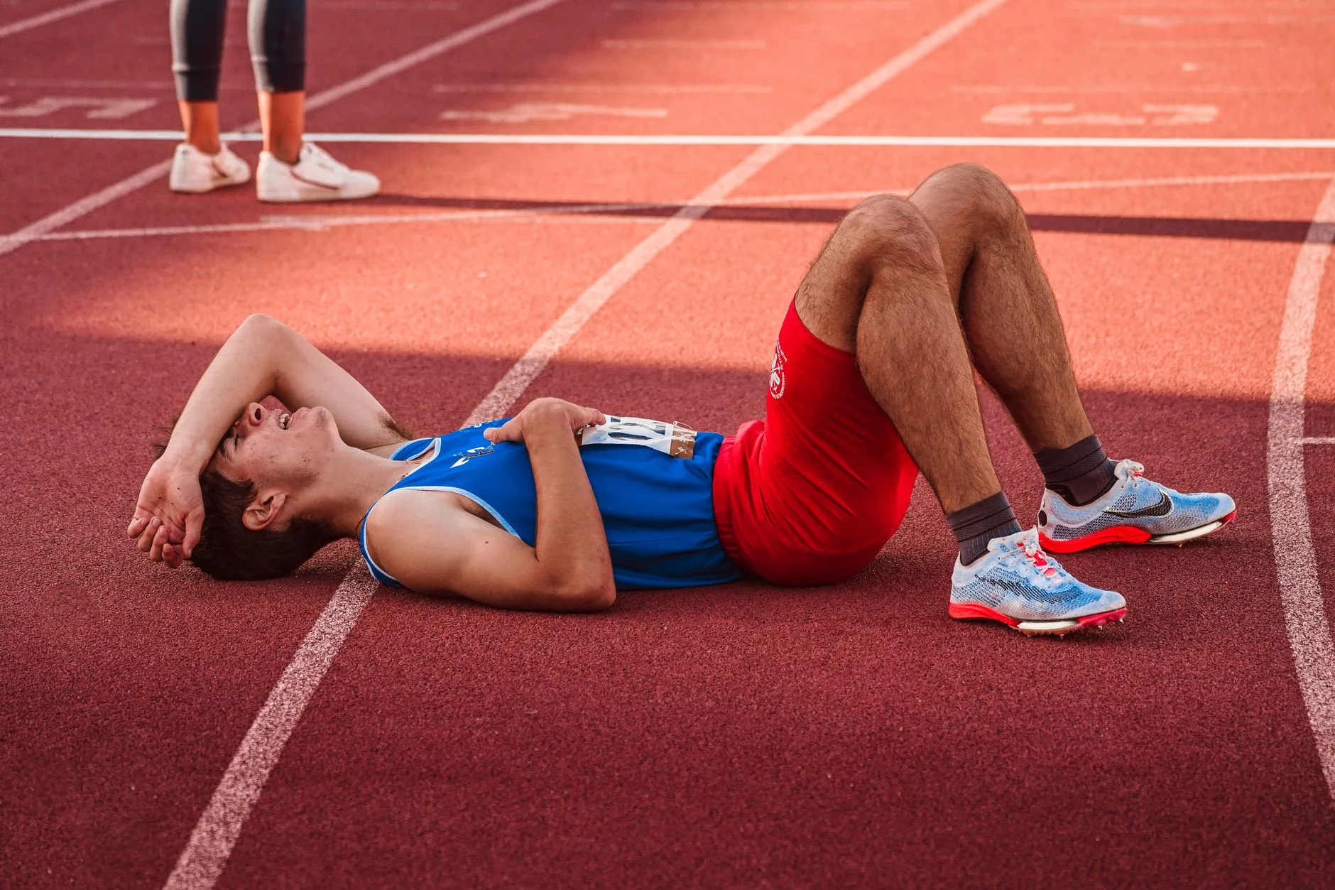 Runner stretching plantar fascia on track, focusing on foot and heel pain relief