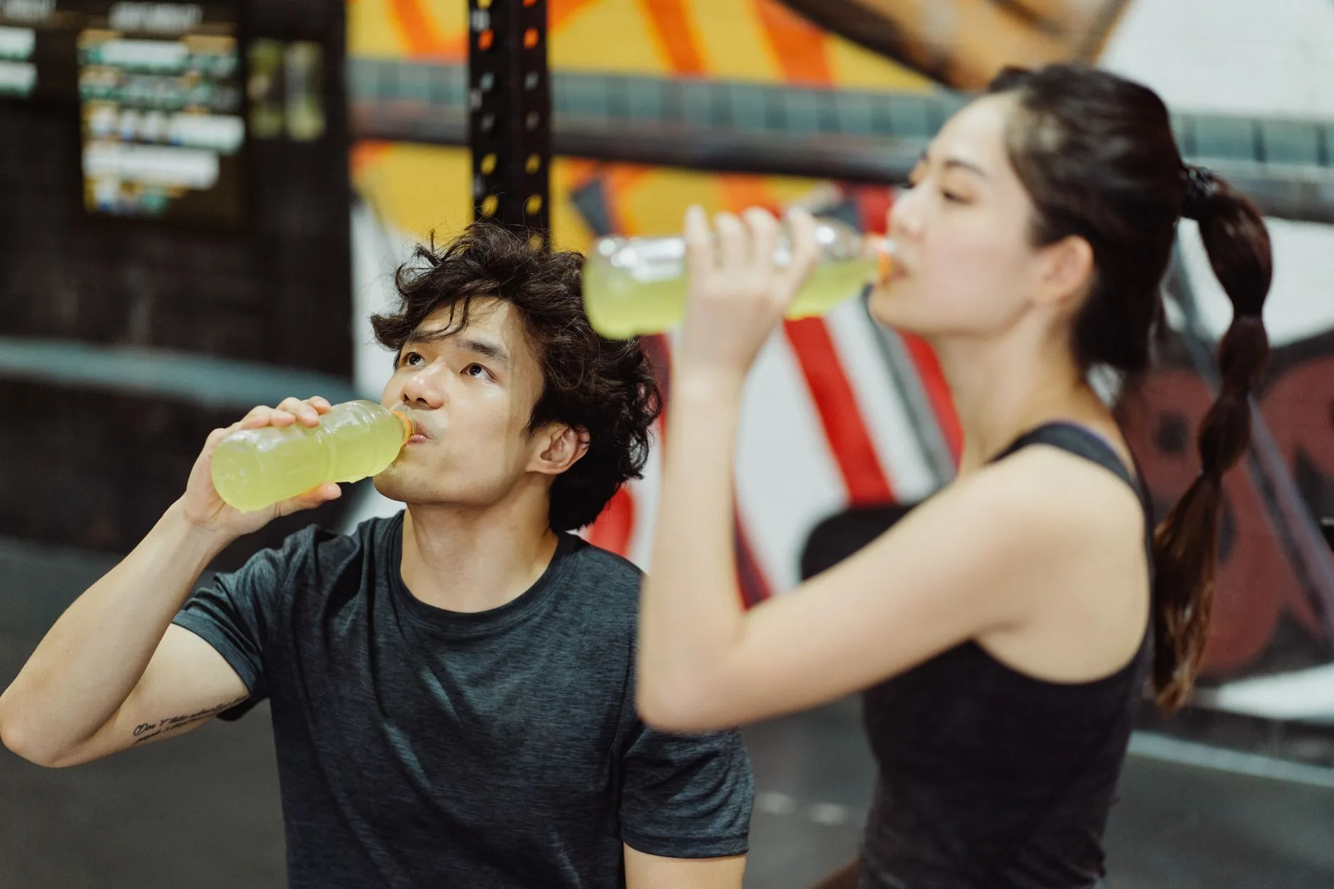 Runner drinking from a bottle mid-race, surrounded by electrolyte drink packets