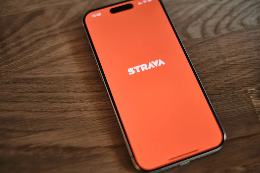 Runner checking Strava app data on smartphone while pausing during an outdoor training run