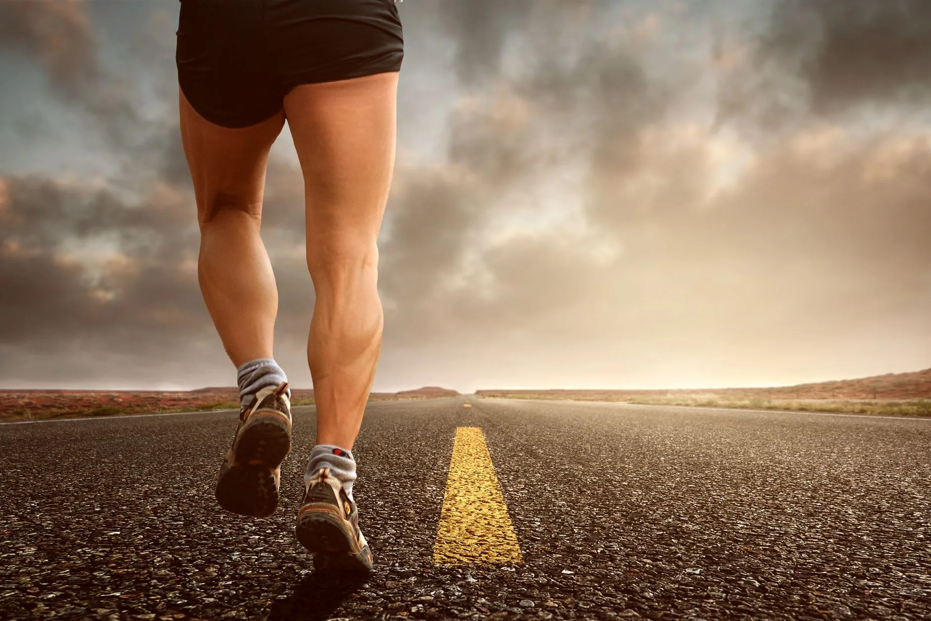 Runner pausing mid-stride to grip calf muscle in pain on outdoor path