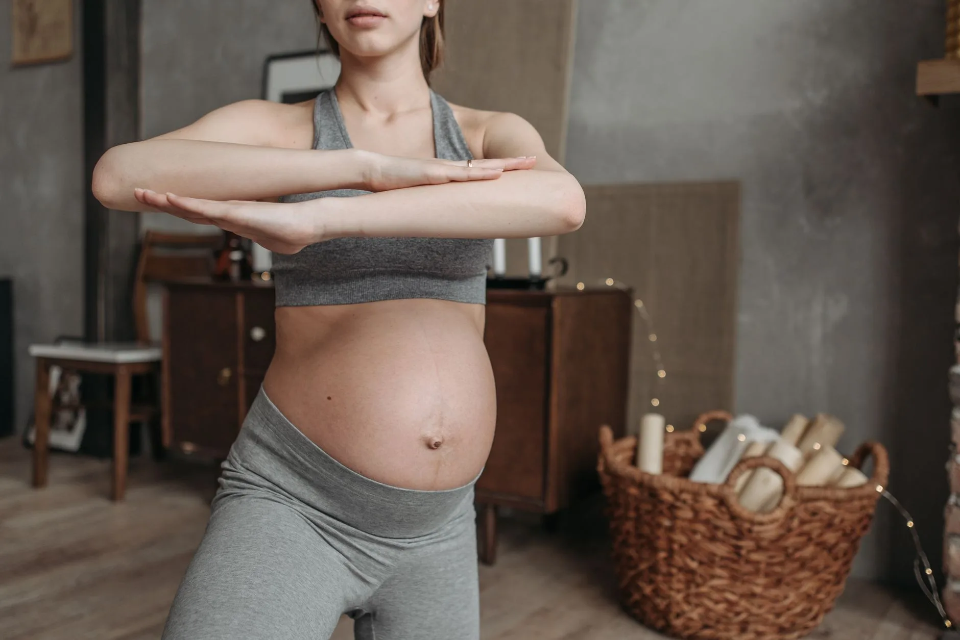 Pregnant woman running outdoors in athletic wear, smiling confidently on a paved trail
