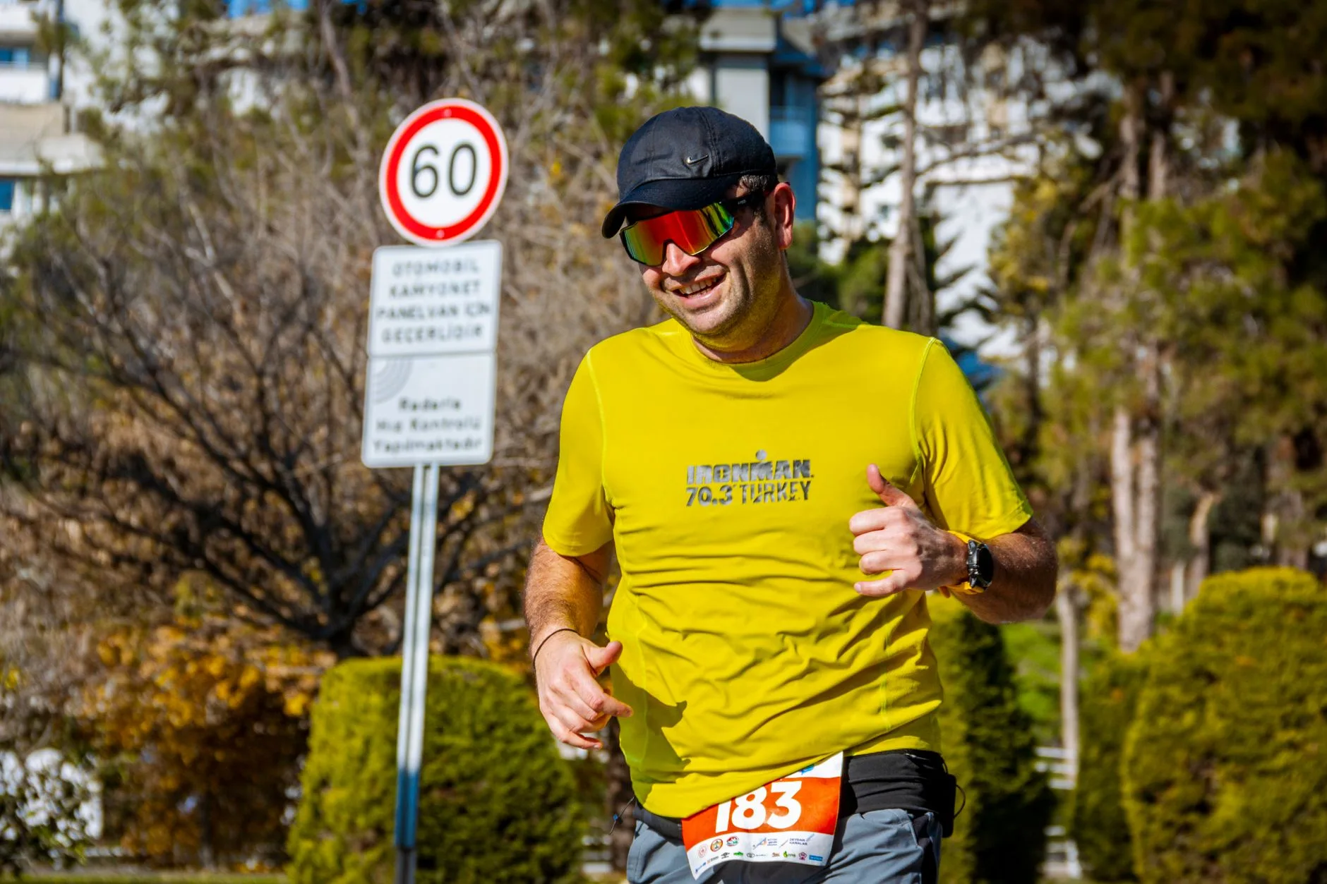 Older runner jogging on a park trail, smiling while training at a steady pace