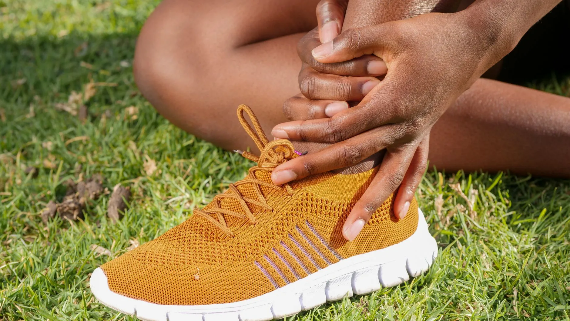 Runner holding Achilles tendon in pain while stopped on a trail