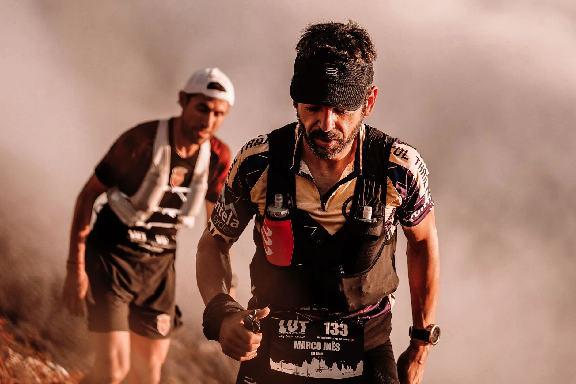 Trail runner trudging up a rugged mountain path during an ultra marathon at dusk