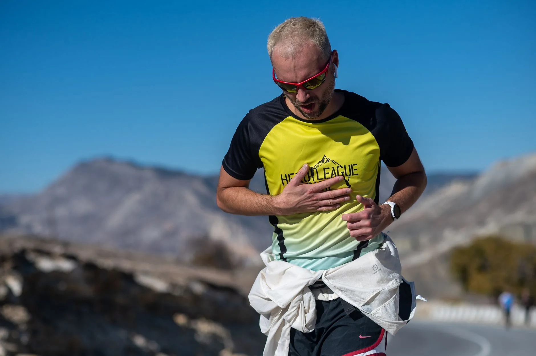 Runner checking heart rate monitor watch while jogging on an outdoor trail