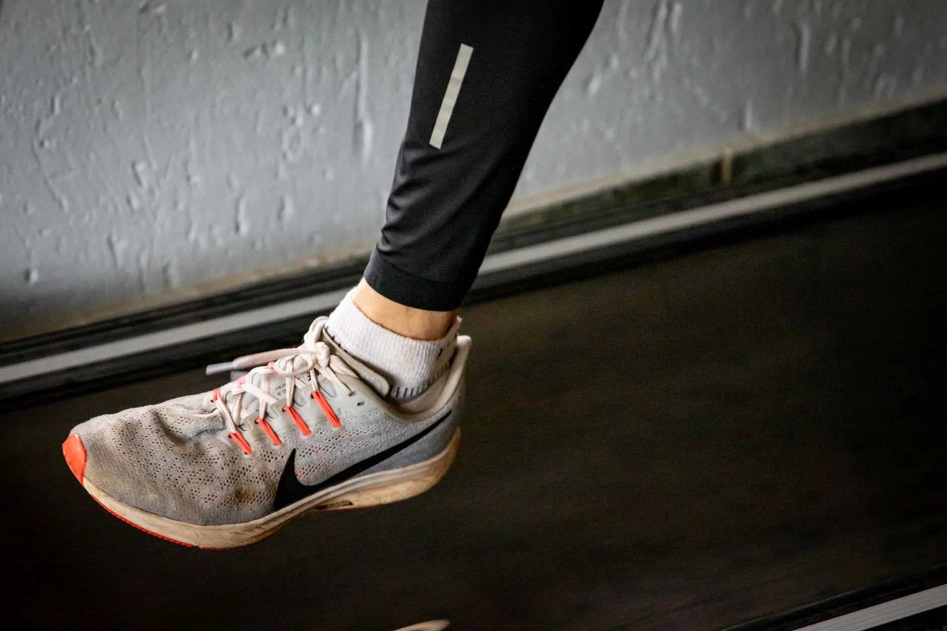 Person measuring thumb's width of space at toe box while trying on running shoe