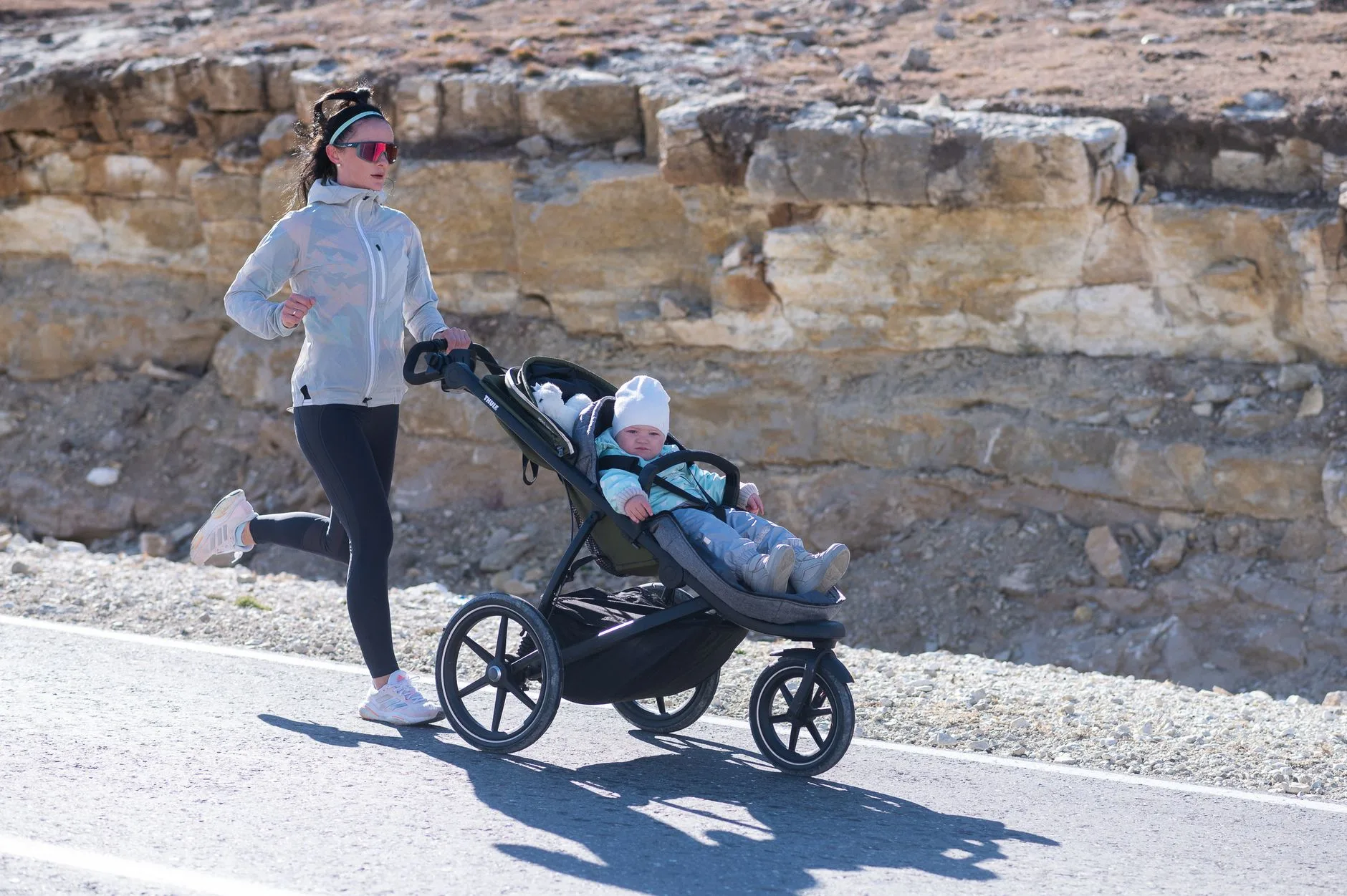 Parent jogging on a park path while pushing a running buggy with one hand