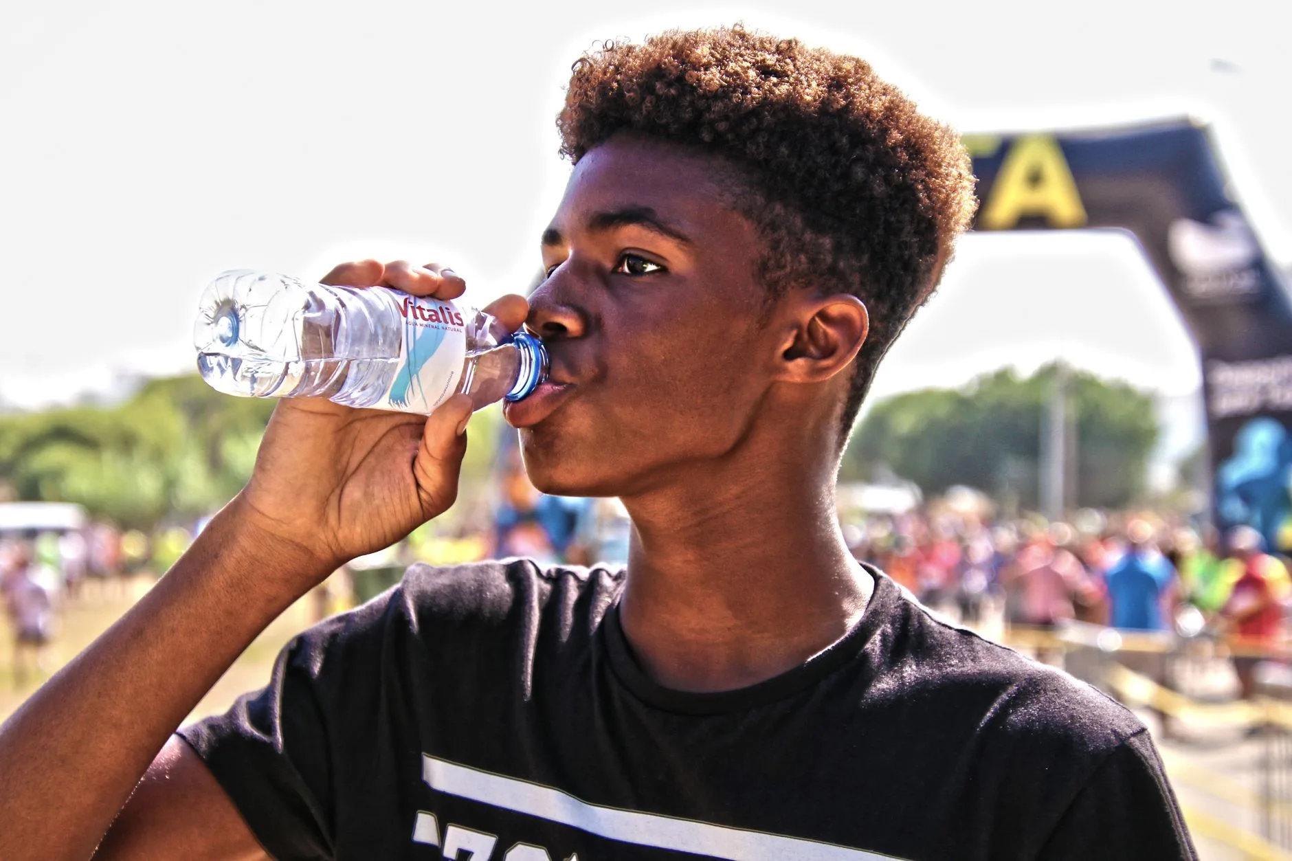 Runner drinking water from a bottle on a sunny summer trail