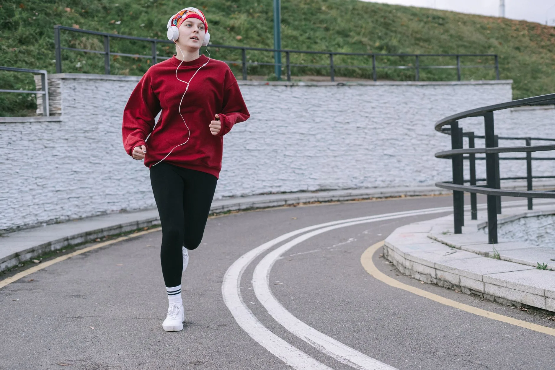 Tired runner pausing mid-stride on a quiet road, hands on hips, fighting to keep going