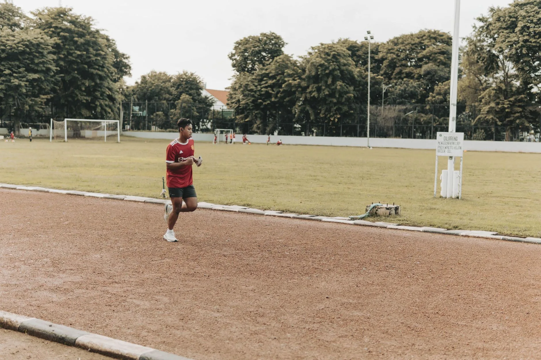 Runner checking a simple fitness watch mid-stride on a quiet morning trail