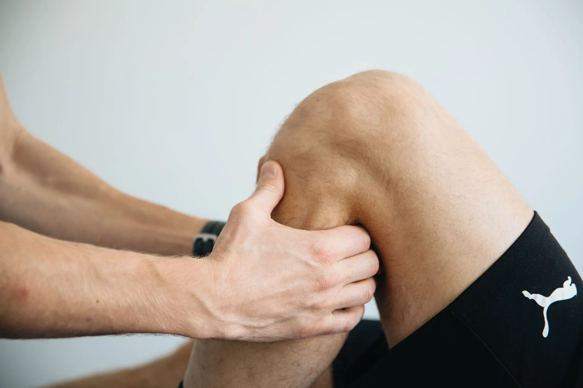 Runner clutching painful knee while jogging outdoors